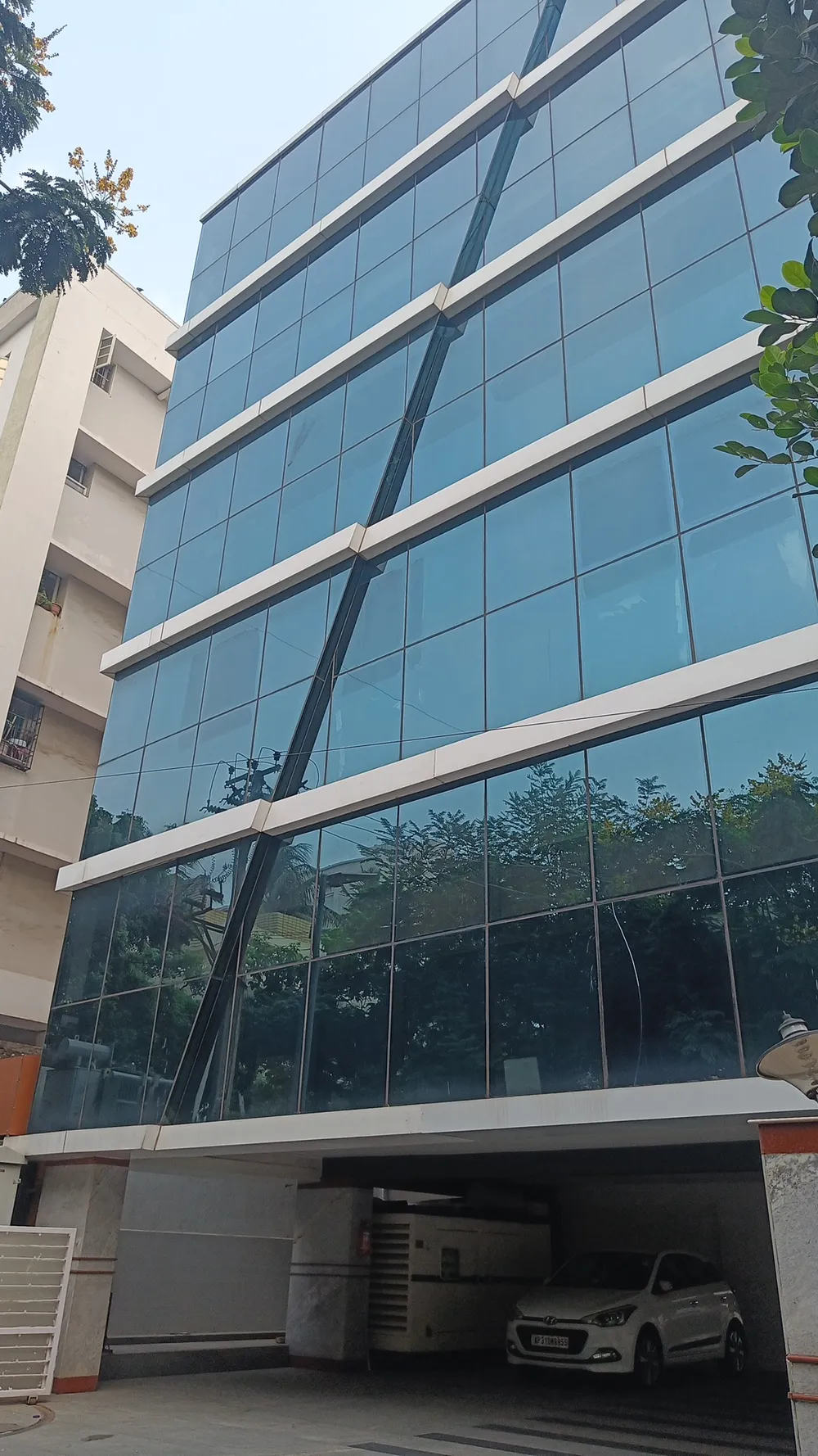 Glass-fronted five-storey building with a car parked in the ground-floor bay