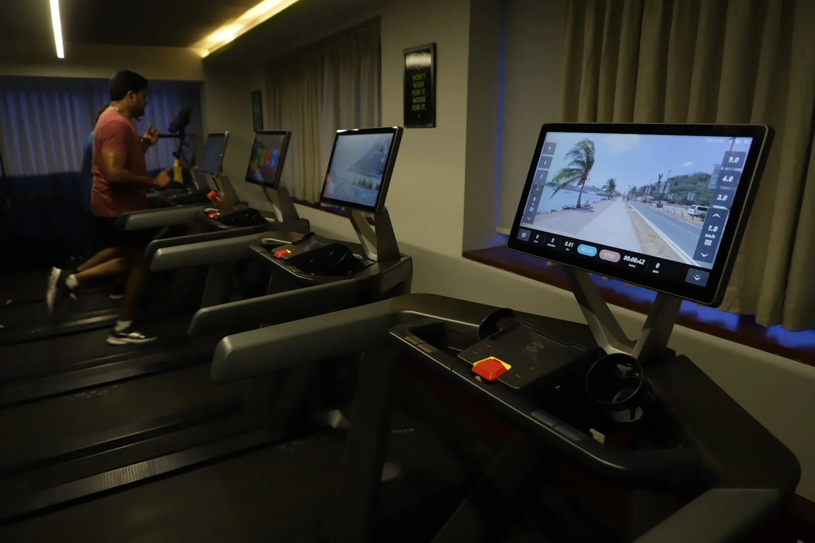 A man running on a treadmill in a row of treadmills with touchscreens